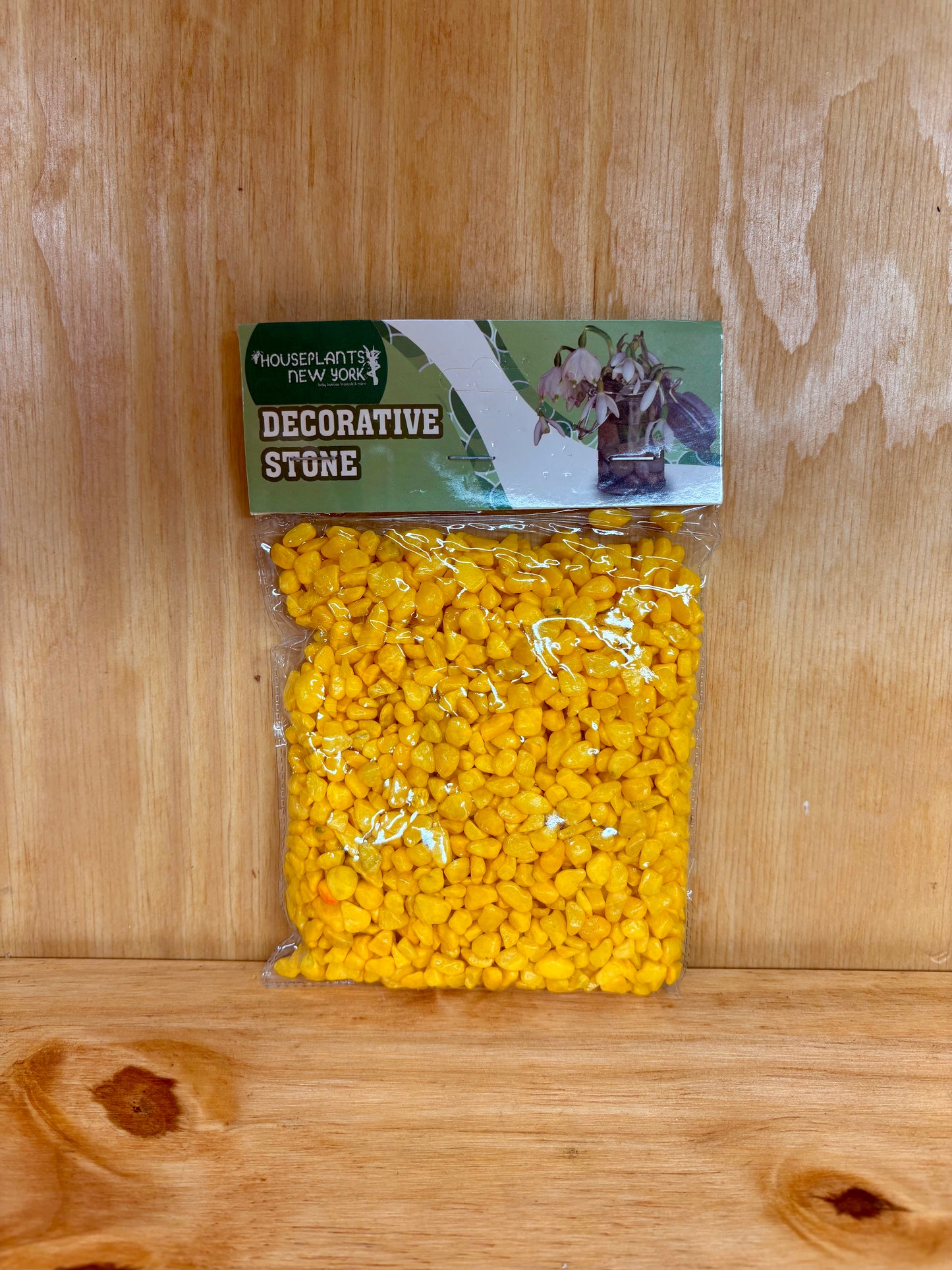Bag of yellow decorative stones with a green label on a wooden surface