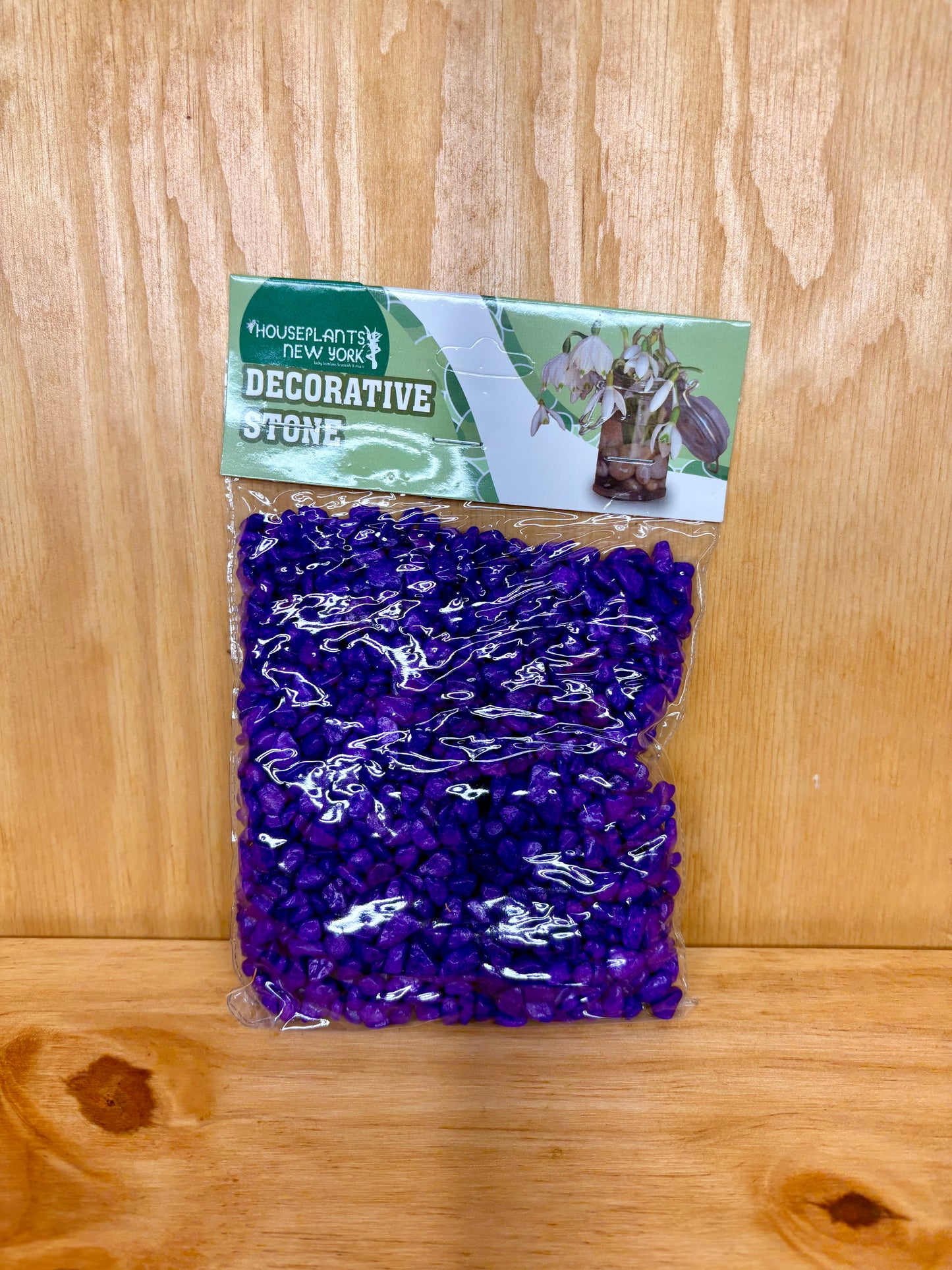 Packaged decorative rock on a wooden surface with a label above it.