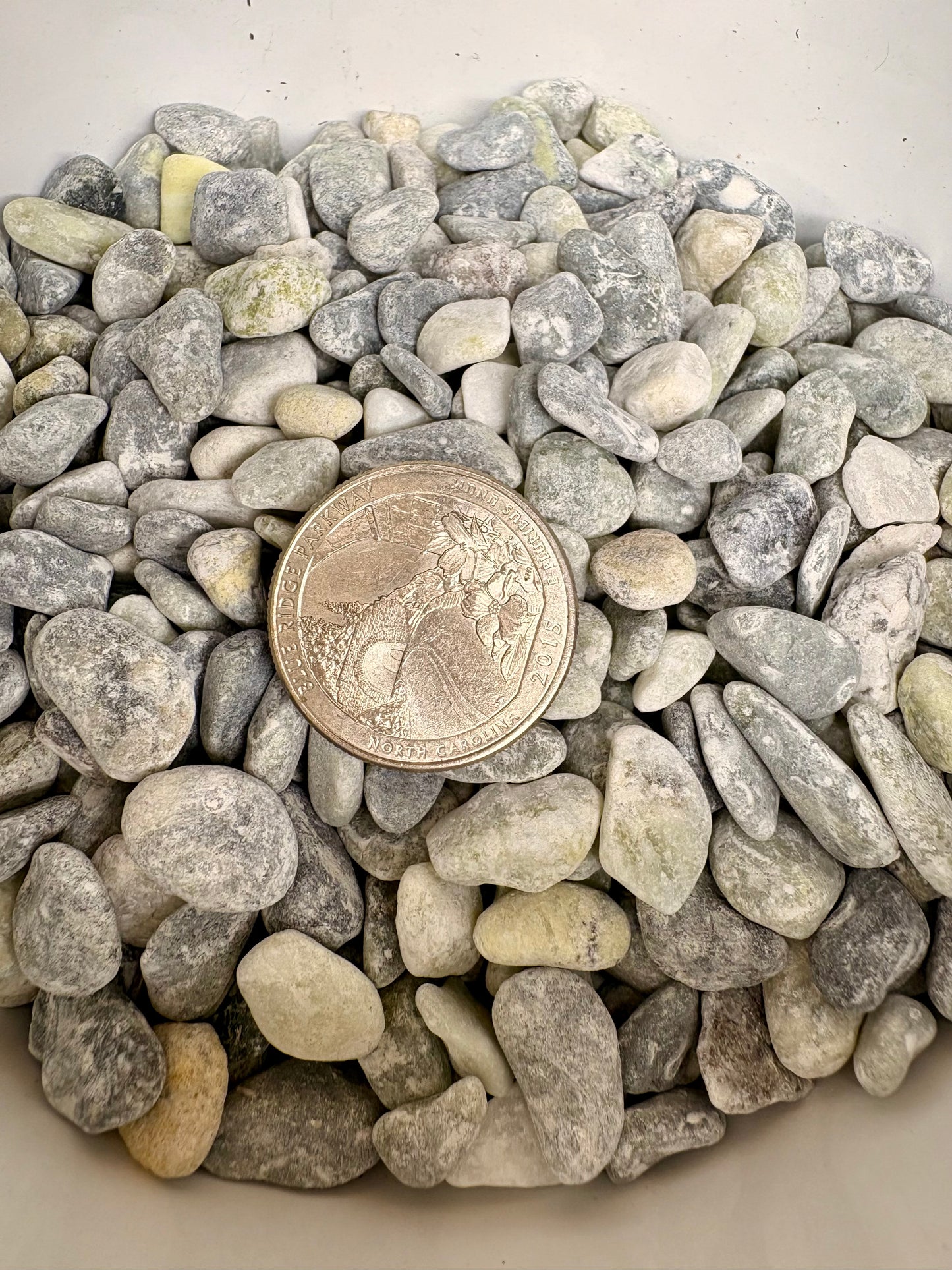 Small stones with a quarter coin for size comparison on a white background