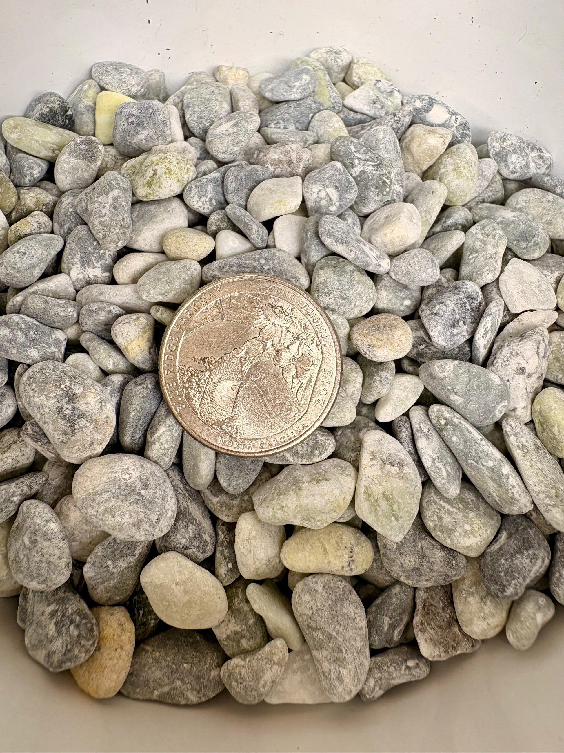 Small stones with a quarter coin for size comparison on a white background